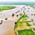 Aerial view of extensive river flooding submerging agricultural fields and farmlands.