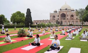 People practicing yoga on red mats outdoors in front of Humayun’s Tomb in Delhi.