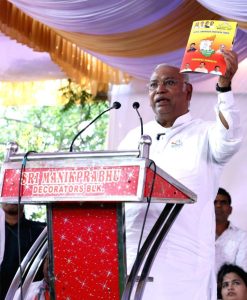 Congress leader Mallikarjun Kharge addressing a rally while holding the party’s election manifesto.
