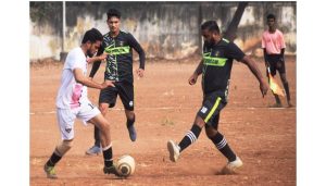 Players competing in an intense football match on a dirt field.