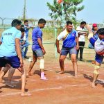 Men playing a competitive match of Kabaddi on an outdoor clay court.