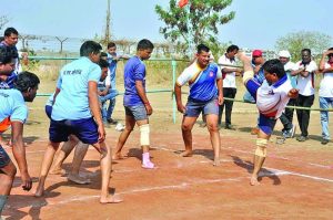 Men playing a competitive match of Kabaddi on an outdoor clay court.